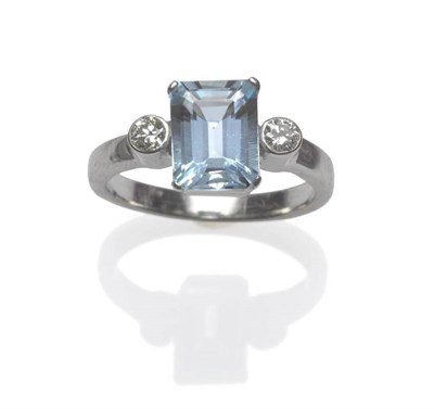 Lot 627 - An Aquamarine and Diamond Three Stone Ring, the oblong step cut aquamarine in a white four claw...