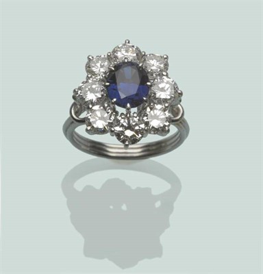 Lot 656 - A Sapphire and Diamond Cluster Ring, the oval cut sapphire within a border of round brilliant...