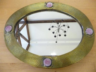 Lot 1215 - An Arts & Crafts Mirror, the oval beaten brass frame with four Ruskin pottery pink roundles...