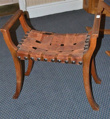 Lot 1283 - An Arts & Crafts Oak Piano Stool, the rectangular seat with interwoven leather straps, brass...