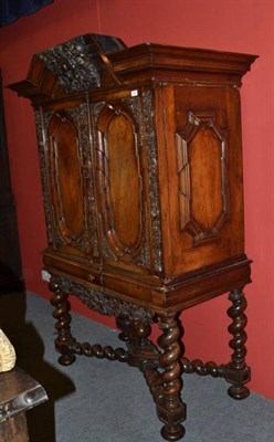 Lot 1443 - An 18th Century German Walnut Cabinet on Stand, the bold pediment above floral and leaf carved...