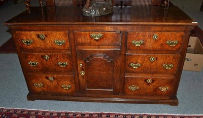 Lot 1557 - An Oak and Walnut Enclosed Dresser, with an arrangement of seven deep drawers around a fielded...