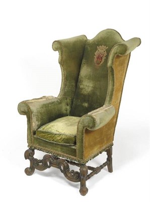 Lot 1697 - An Early 18th Century Style Walnut Wingback Armchair, upholstered in worn green velvet, the...