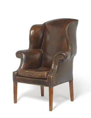 Lot 1699 - A George III Wingback Chair, early 19th century, upholstered in brown close-nailed leather,...