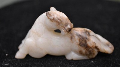 Lot 166 - A Chinese Carved Jade Model of a Recumbent Horse, in late Ming style, the animal turns to face...