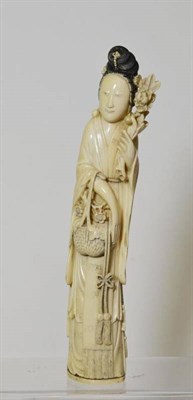 Lot 195 - A Chinese Ivory Figure of a Maiden, 19th century, standing wearing flowing robes, a flowering...