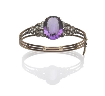 Lot 365 - A Victorian Amethyst and Diamond Bangle, a central oval mixed cut amethyst within yellow double...