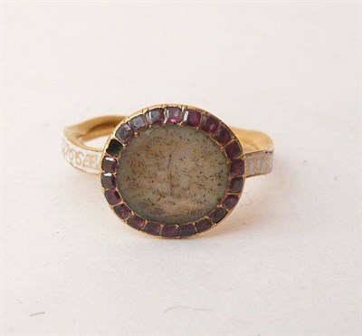 Lot 370 - A George III Mourning Ring, a locket panel centres a border of foil backed garnets, to a wavy...