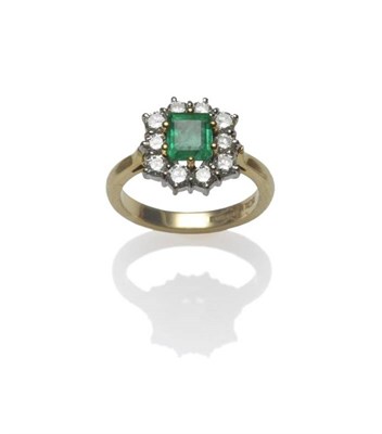 Lot 379 - An 18 Carat Gold Emerald and Diamond Cluster Ring, the step cut emerald with truncated corners in a