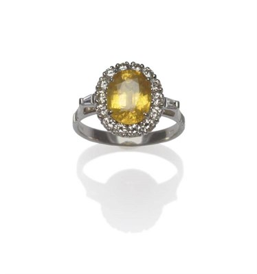 Lot 406 - An 18 Carat White Gold Yellow Sapphire and Diamond Cluster Ring, the yellow oval mixed cut sapphire