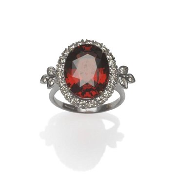 Lot 413 - An 18 Carat White Gold Garnet and Diamond Cluster Ring, the oval mixed cut garnet within a...