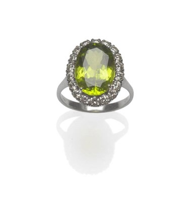 Lot 416 - An 18 Carat White Gold Peridot and Diamond Cluster Ring, the oval cut peridot within a border...