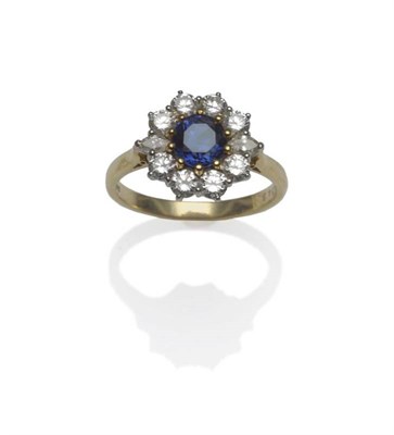 Lot 435 - An 18 Carat Gold Sapphire and Diamond Cluster Ring, a round brilliant cut sapphire in a yellow claw