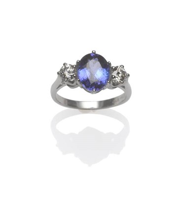 Lot 439 - A Tanzanite and Diamond Three Stone Ring, the oval cut tanzanite flanked by a round brilliant...