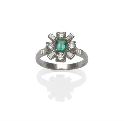 Lot 470 - An 18 Carat White Gold Emerald and Diamond Cluster Ring, the central step cut emerald in yellow...