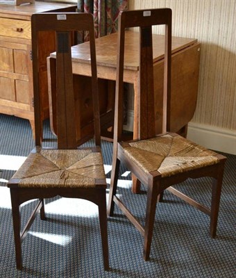 Lot 1100 - A Pair of Arts & Crafts Inlaid Oak Side Chairs, the splat with floral inlay motif, rush seats,...