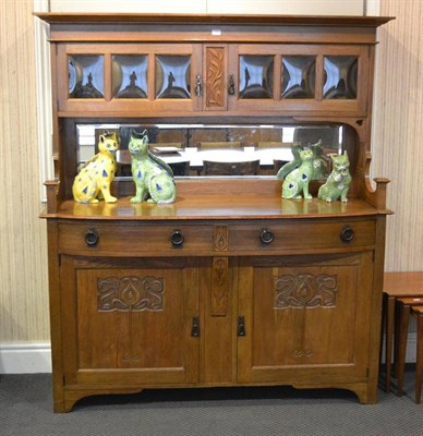 Lot 1103 - An Arts & Crafts Carved Oak Sideboard, the superstructure with moulded cornice over two glazed...