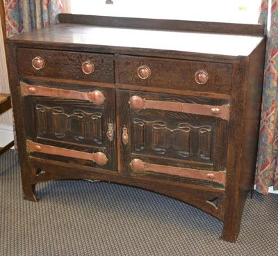 Lot 1104 - An Arts & Crafts Oak Sideboard, with raised upstand above a canted rectangular top, over two...