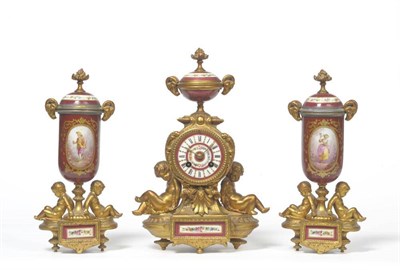 Lot 1143 - A Gilt Metal Porcelain Mounted Mantel Clock Garniture, circa 1890, surmounted by an urn finial,...