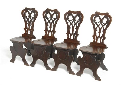 Lot 1343 - A Set of Four George III Mahogany Hall Chairs, circa 1820, the gothic tracery pierced splats...