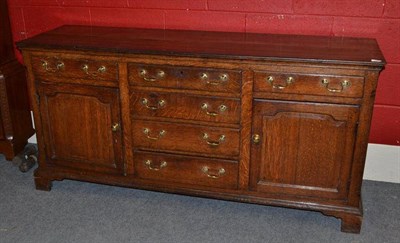 Lot 1392 - A George III Oak Enclosed Dresser Base, late 18th century, with six long drawers around two fielded