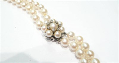 Lot 40 - A double row long length cultured pearl necklace with a diamond-set cluster clasp
