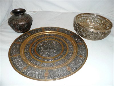 Lot 262 - A Burmese white metal bowl decorated in relief with figures, a similar charger and bowl (3)