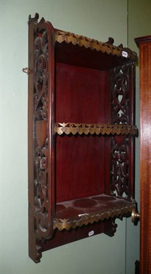 Lot 965 - A mahogany and brass mounted hanging book shelf with scroll fretted armorial side panels