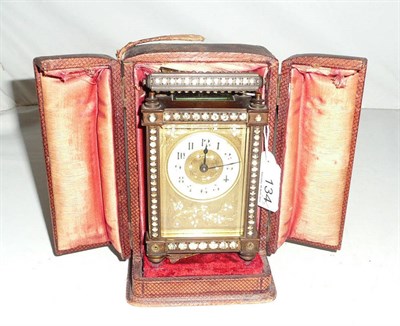 Lot 134 - A French brass carriage clock embellished with clear paste jewels, in fitted travelling case...