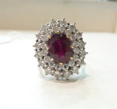 Lot 247 - An 18ct gold ruby and diamond cluster ring, an oval cut ruby within a double border of round...