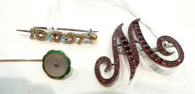 Lot 413 - A garnet-set initial 'M' brooch, a turquoise and seed pearl date brooch and an enamelled pin