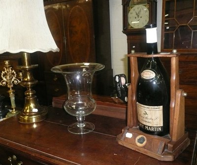 Lot 568 - Large Cognac bottle in wooden cradle, large plain glass urn and a brass table lamp