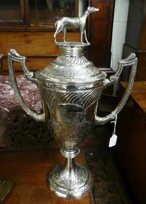 Lot 570 - A silver plated trophy cup, engraved with a coursing scene and a cover with greyhound finial