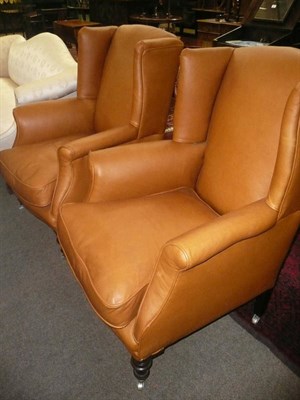 Lot 775 - A pair of brown leather wing back chairs, with padded back support and squab cushion between...