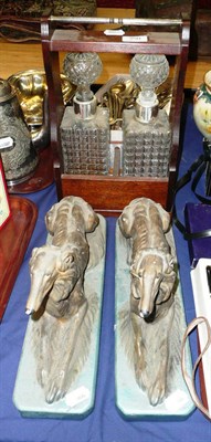 Lot 350 - Two bottle tantalus with plated mounts and two plaster groups of reclining dogs (3)