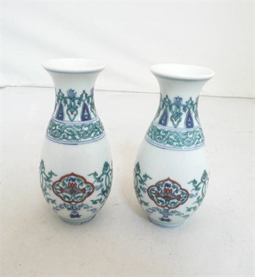 Lot 382 - A pair of Chinese Doucai porcelain vases, of skittle shape, decorated with formal scrolls,...