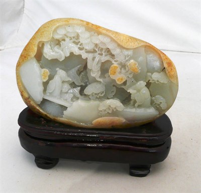 Lot 503 - A jade-type boulder carving, worked with figures and birds in a landscape, on a carved wood stand