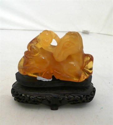 Lot 504 - A Chinese amber-type carving of a monkey on the back of a horse, on a carved and pierced wood stand