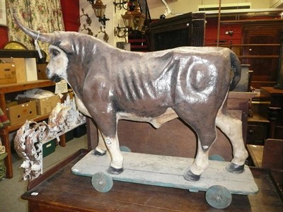 Lot 1124 - A papier mache painted bull on a rectangular base with wheels