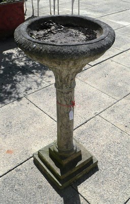 Lot 1312 - A cast composition stone bird bath, the circular top on a single stem and stepped square base,...