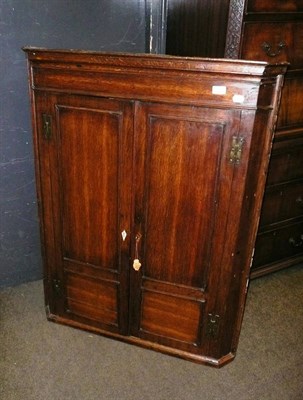 Lot 669A - An 18th century oak hanging corner cupboard, with conforming fielded panel door and H hinges...