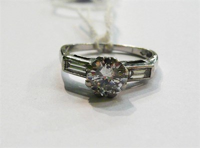 Lot 29 - A platinum diamond ring, a diamond solitaire in a white eight claw setting, with a baguette cut...