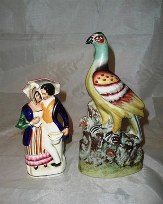 Lot 142 - A Staffordshire pottery peacock and a Staffordshire figure group of a couple with umbrella,...