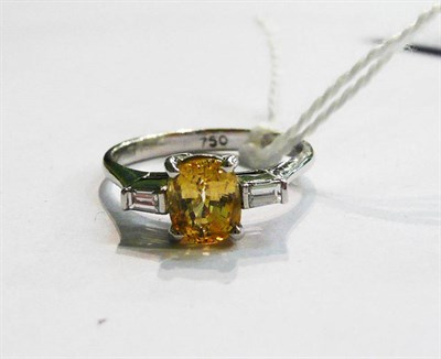 Lot 226 - An 18ct white gold yellow sapphire and baguette cut diamond three stone ring