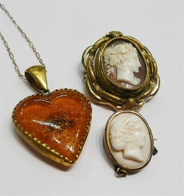 Lot 422 - Two cameo brooches and an amber pendant on chain