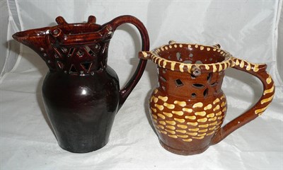 Lot 82 - A 19th century slip decorated puzzle jug (handle re-glued) and a treacle glazed puzzle jug with...