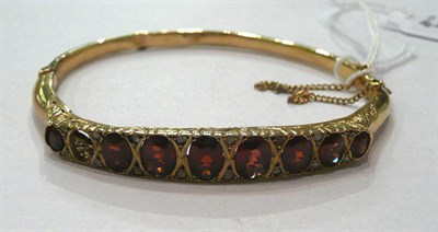 Lot 347 - A 9ct gold graduated garnet bangle, with diamond detail NB One garnet missing