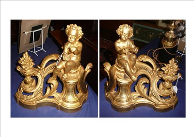 Lot 532 - A pair of French gilt brass chenets, circa 1850, each worked with a seated cherub holding a nest of