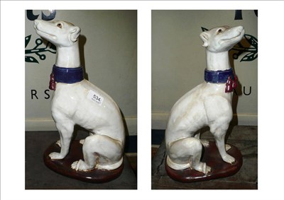 Lot 534 - A large pair of ceramic greyhounds, modelled in seated position