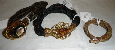 Lot 594 - Three Victorian hair Bracelets, one of plaited fair hair, mounted with a snake's head and tail,...